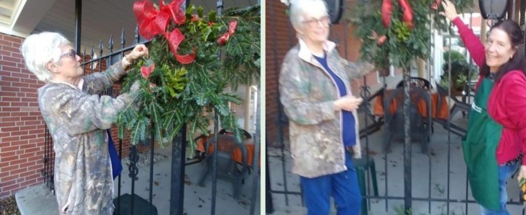 Women decorating Bishop House with red bows and garland