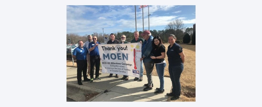 People holding thank you Moen banner