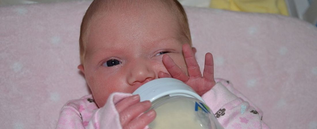 baby with bottle and waving