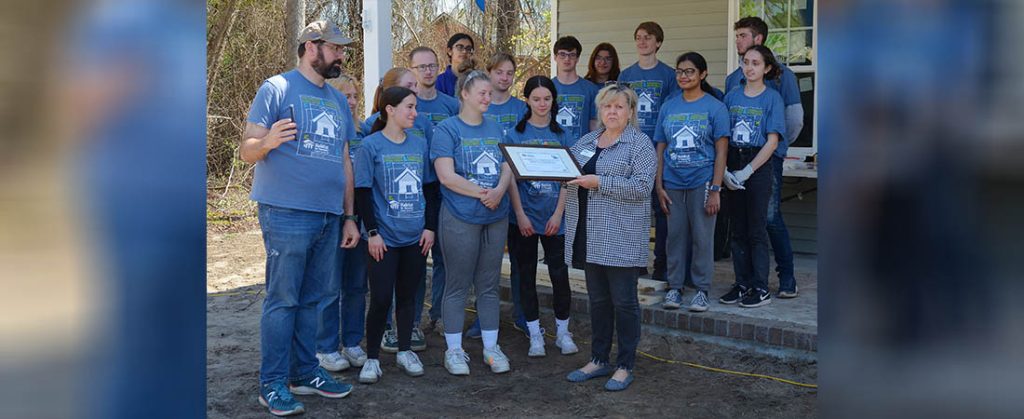 Rose MacNeal, Habitat for Humanity board president and chair, presents a certificate to students and alumni from the University of Delaware thanking the school for its help with Habitat home building projects over the last decade. Photo by Todd Wetherington.