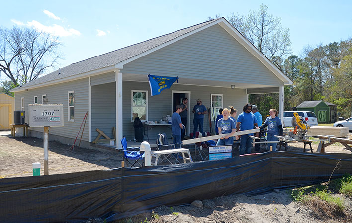 Students from the University of Delaware join Habitat for Humanity volunteers as they work to complete a new home on Aycock Avenue in New Bern's Pembroke community. Photo by Todd Wetherington.