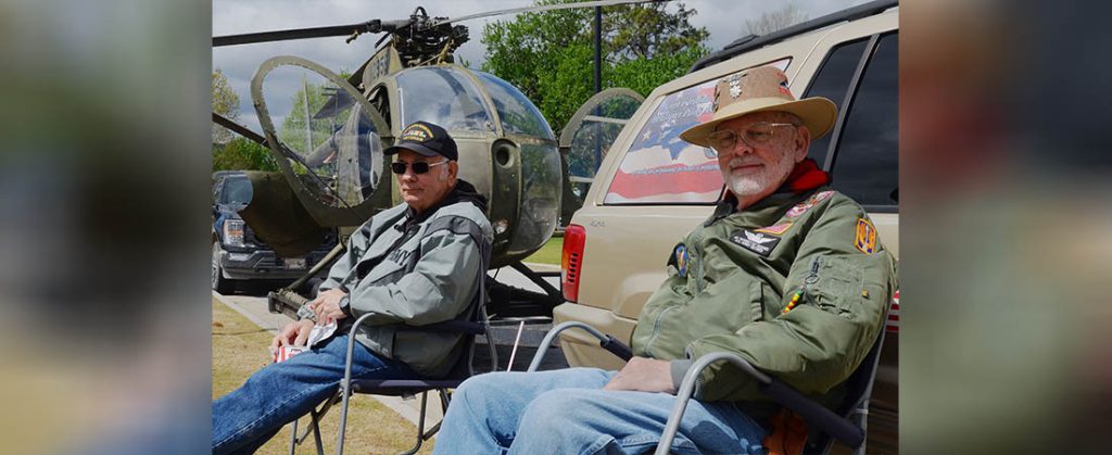 Ed Hughes, right, and Danny Elzie, Army veterans who served in the Vietnam War, sit near a Hughes OH-6 Cayuse helicopter Wednesday's Vietnam War Veterans Day recognition event at Union Point Park. Photo by Todd Wetherington.