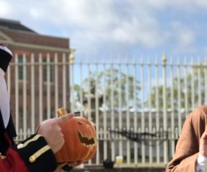 Man with missing head holding pumpkin at scared man