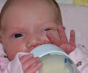 baby with bottle and waving