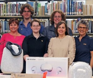 Alpha Phi Nu members in front of equipment