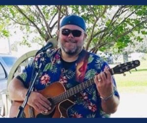 Sam Lewis holding a guitar